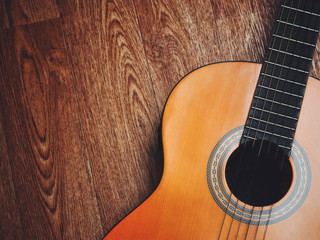 Acoustic guitar resting against a wooden background with copy space.