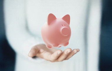 Mano con porcellino salvadanaio, risparmio o investimento