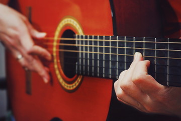 Fototapeta premium Guitar in the hands. Plays guitar. Guitar Strings. Guitar in vintage style