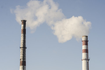 A coal-fired plant produces smoke into the sky, thereby sucking up the earth's atmosphere. Smoke from a chimney against a blue sky