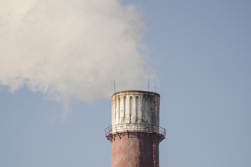 A coal-fired plant produces smoke into the sky, thereby sucking up the earth's atmosphere. Smoke from a chimney against a blue sky