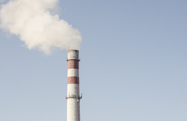 A coal-fired plant produces smoke into the sky, thereby sucking up the earth's atmosphere. Smoke from a chimney against a blue sky
