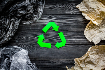 Eco-friendly life. Green paper recycling sign among waste paper, plastic, polyethylene on grey...