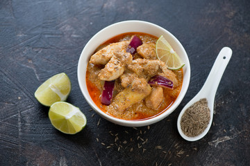 Thai massaman curry with chicken meat and potato on a dark brown stone background, studio shot