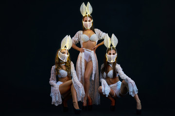 Group of Sexy girsl in white lingerie and LED masks. Go-go dancers. Three Strippers posing in the...
