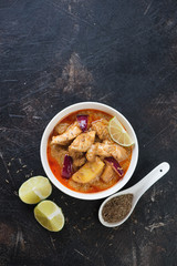 White bowl with thai massaman curry on a dark brown stone background, vertical shot with copyspace, above view