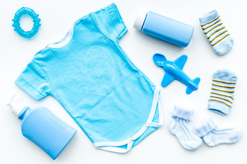 Blue set for newborn boy. Baby bodysuit, socks, airplan toy, soap and powder on white background top view