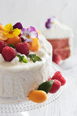 Festive cake with raspberries and flowers with streaks of glaze on  white background