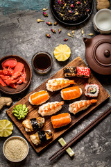 sushi and sushi rolls, sushi nigiri on stone plate on dark background, mustard wasabi, and ginger
