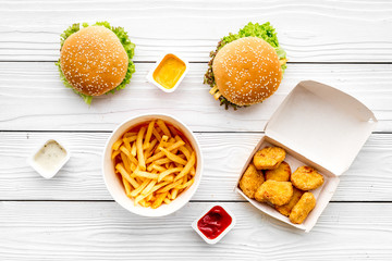 Most popular fast food meal. Chiken nuggets, burgers and french fries on white wooden background top view