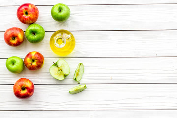 Apple cider vinegar in bottle among fresh apples on white wooden background top view copy space