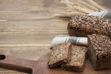 Fitness bread. A loaf of fresh rustic whole meal rye bread, sliced on a wooden board, rural food background. Copy space.