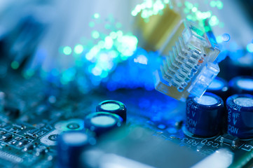 Yellow internet switch close up macro shot on computer circuit board, green, blue optical fibres.