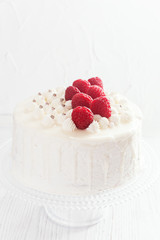 Festive cake with raspberries and flowers with streaks of glaze on  white background
