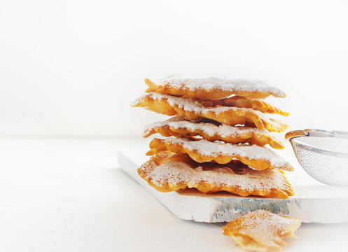 Italian Frappe or chiacchiere  - typical Italian carnival fritters dusted with powdered sugar on  white wooden table. With free text space.