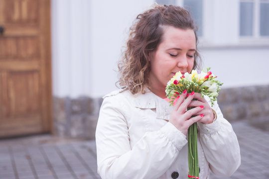 Beautiful portrait of curly woman holding flowers at the park.