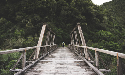 Fototapeta na wymiar Hiker Walking Across Old Wooden Bridge
