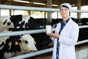 Mature woman veterinarian with milk at cowshed