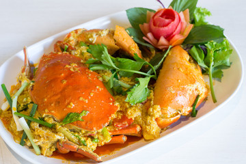 Stir-fried crab with curry powder and fried egg in white dish on table.