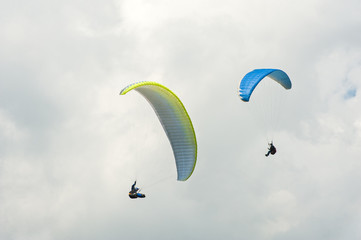 Two paragliders flying in the blue sky against the background of clouds. Paragliding in the sky on a sunny day.