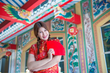 Portrait of beautiful asian woman in Cheongsam dress with Red envelope in hand,Thailand people,Happy Chinese new year concept