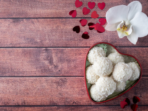 Coconut candy in a red heart Orchid Flower Wooden Background Copy space