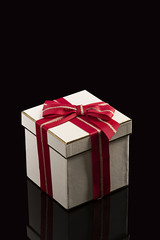 Caja de regalo con lazo rojo sobre fondo negro.