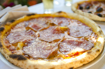 Delicious fresh pepperoni and salami wood fired oven baked thin crust pizza for dinner in Sardinia, Italy