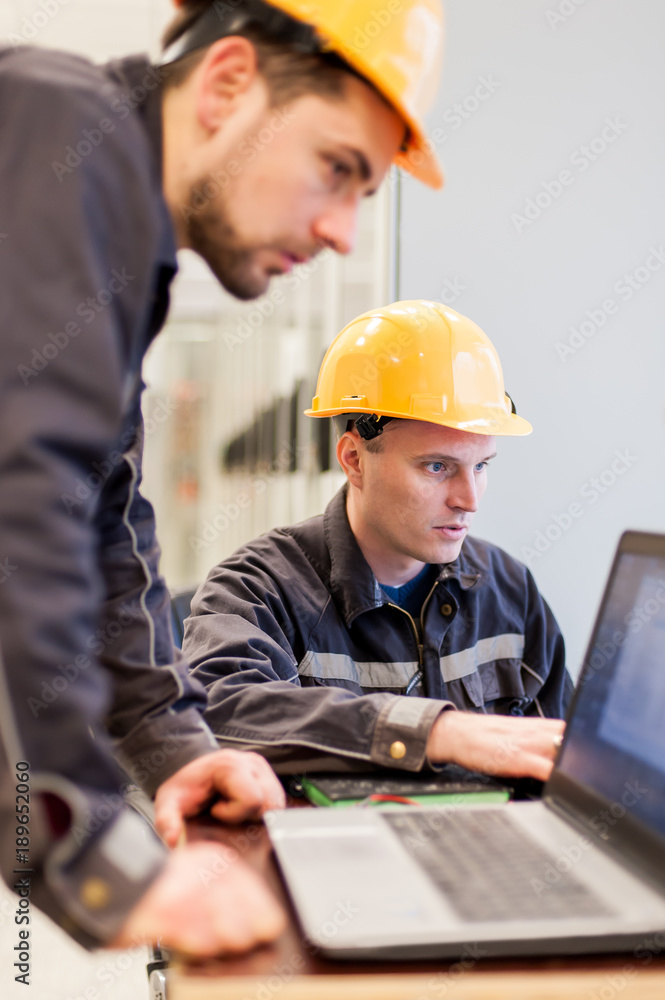 Wall mural field service engineers inspect relay protection system with laptop computer