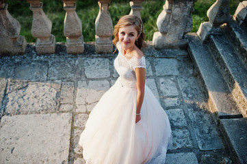 Portrait of an attractive bride standing by to the castle on her wedding day.