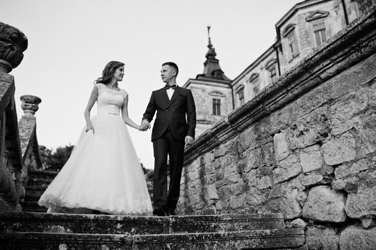 Fabulous wedding couple walking around the castle territory on their festive day. Black and white photo.