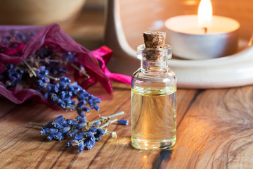 Obraz na płótnie Canvas A bottle of lavender essential oil with dried lavender twigs