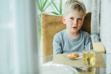 Preschooler baby boy drinking tea at kitchen. Close up