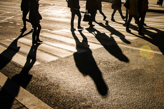 Blurry people and their shadows on crossing