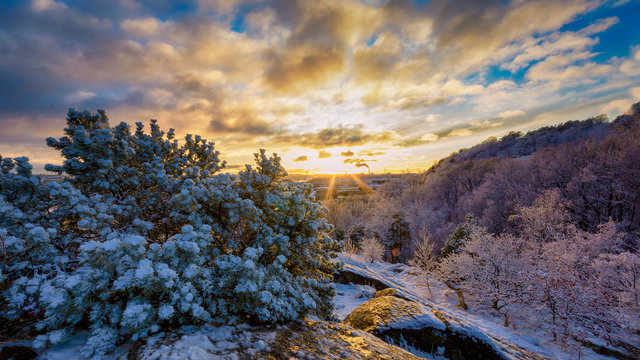 Snow filled mountain over Ramberget hill with setting sun creating sun star , Gothenburg, Sweden 