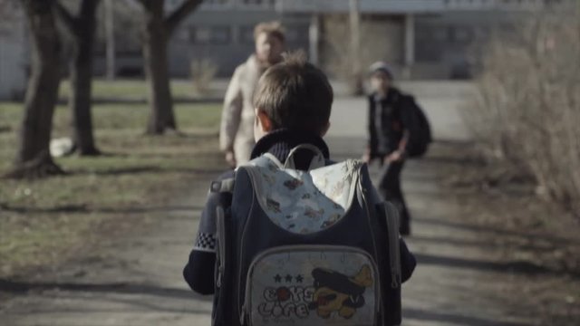 Little boy with a backpack go to school. Back view. Boy with a backpack walking in the Park. Concept of lonely