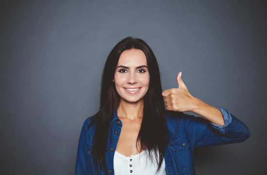 Everything Will Be Cool. Beautiful Smiling Confident Woman In A Denim Shirt Showing A Hand Sign Ok On A Gray Background Isolated.