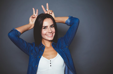 Portrait of a beautiful smiling modern girl in a denim shirt which poses in front of the camera on a gray background isolated.