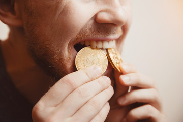 Bitcoin. Man bites a gold coin with his teeth