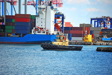 Tugboat assisting container cargo ship