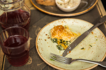khachapuri with spinach, egg and cheese on old plate. jug with compote