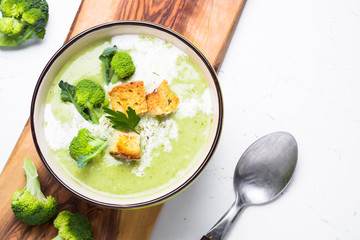 Green soup puree with broccoli. Top view on white table.