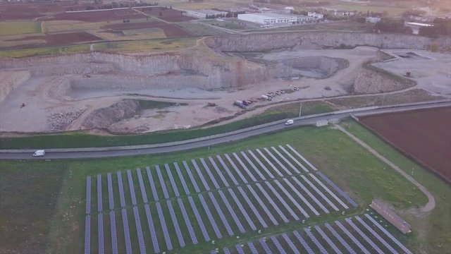 solar panels near a quarry and trucks pass along the road