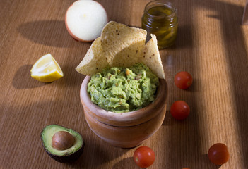 bowl of homemade guacamole with tortilla chips on rustic table