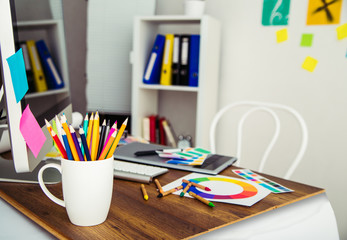 Modern office workplace with digital tablet, notepad, colorful pencils, glasses, in morning