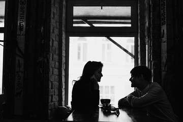 девушка и парень сидят в кафе напротив окна a girl and a guy are sitting in a cafe in front of the window