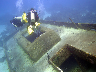 Scuba divers explore the wreck of a sunken boat.