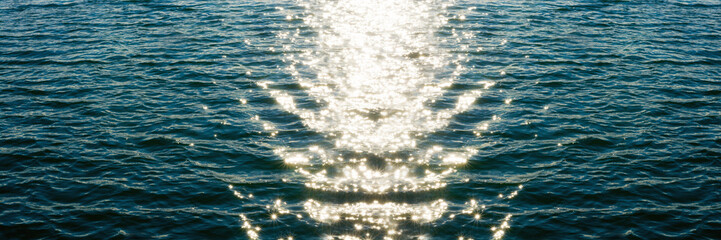 Sea ripples. Bright background. Dark green water. Shallow waves and sun glare on the water. Abstract.