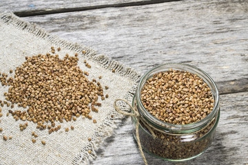 Raw buckwheat in a glass jar on a wooden table.