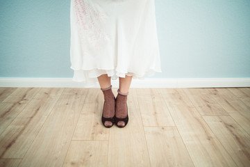 Frauenfüße mit Socken und High heels auf Holzfußboden